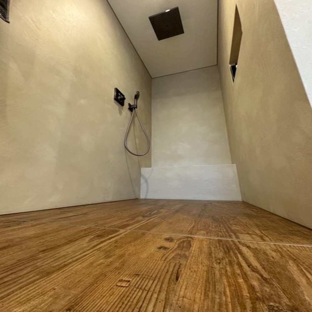 Wanddekoration mit grau-buntem Druck einer brausenden Welle. Der Fußboden ist aus Holzdielen.